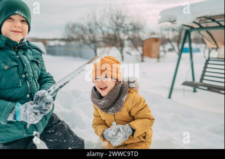 Cheerful siblings playing with icicle in snow Stock Photo