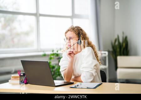 Customer service representative talking through headset at call center Stock Photo
