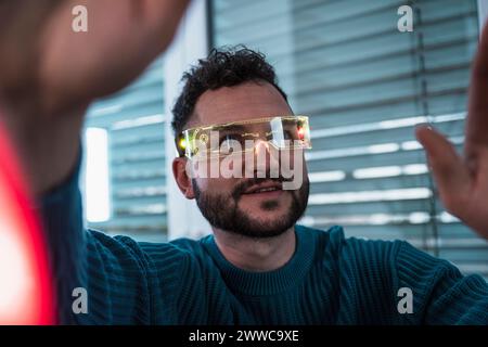 Smiling man wearing smart glasses and gesturing at home Stock Photo
