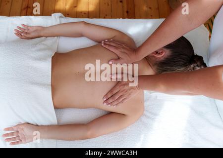 Osteopath massaging patient's back in treatment room Stock Photo