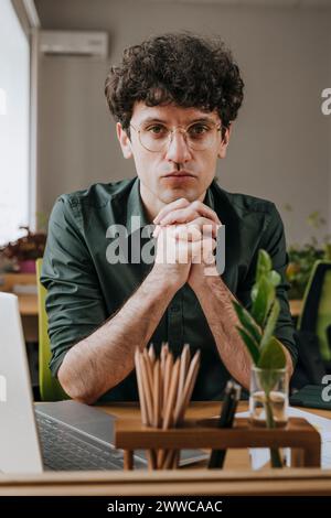 Serious businessman leaning on elbows near laptop in office Stock Photo