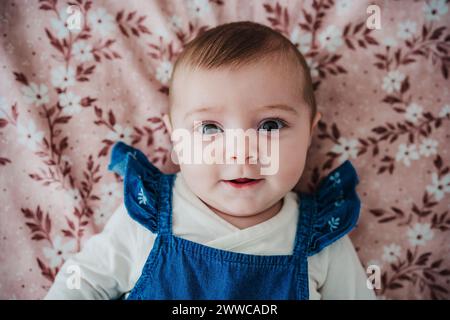 Baby girl lying on bed in bedroom Stock Photo