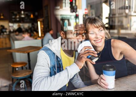 Curious multiracial friends drinking coffee and looking out of window Stock Photo