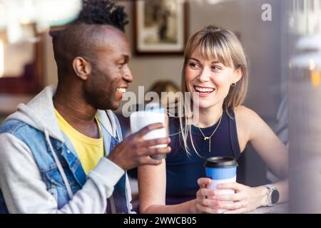 Smiling blond woman having coffee with friend at cafe Stock Photo