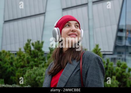 Happy young woman wearing wireless headphones listening to music Stock Photo