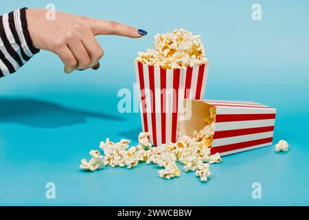Hand of woman touching popcorn in red striped container Stock Photo