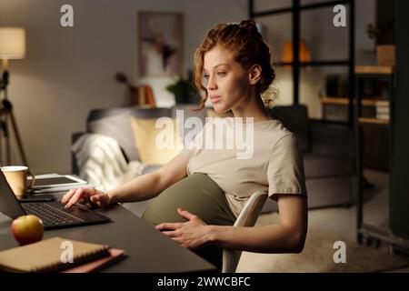 Pregnant woman working on laptop from home Stock Photo