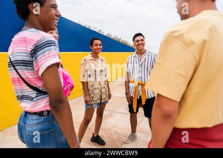 Cheerful friends chatting next to colorful wall Stock Photo