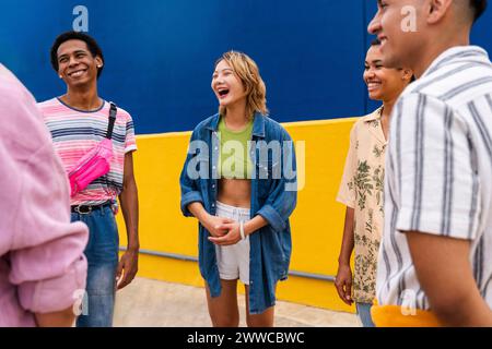 Cheerful friends chatting next to colorful wall Stock Photo