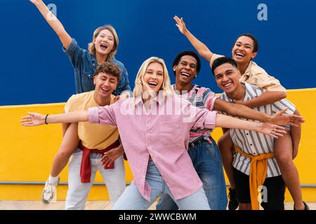 Group of young friends with colorful clothing posing happily in front of wall Stock Photo