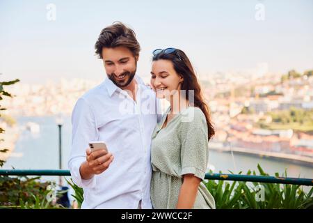Happy young couple using smart phone on sunny day Stock Photo
