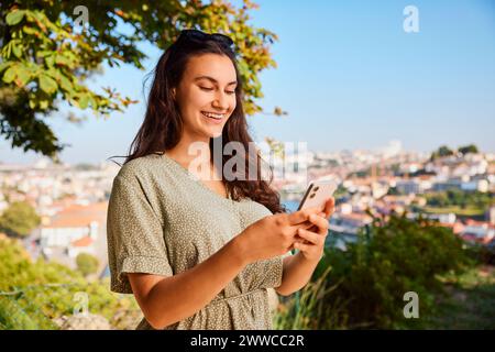 Smiling young woman using smart phone Stock Photo