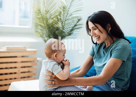 Happy mother playing with daughter sitting in bedroom Stock Photo