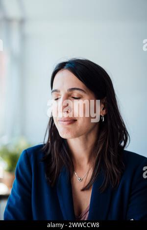 Smiling businesswoman with eyes closed at home Stock Photo