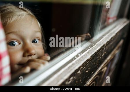 Girl looking out through window Stock Photo