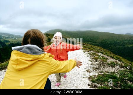 Happy girl running towards mother crouching on mountain Stock Photo