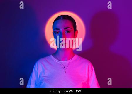 Woman in neon lighting against gradient background Stock Photo