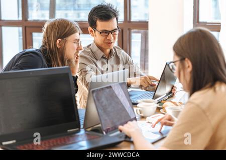 Programmers discussing over laptop near businesswoman working at startup Stock Photo