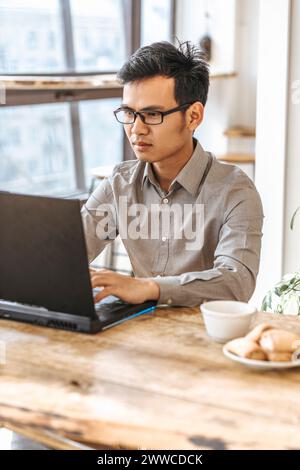 Confident young programmer using laptop for coding at creative startup Stock Photo