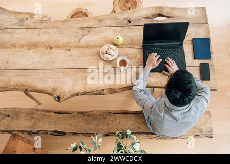 Young IT technician using laptop at table working in creative office Stock Photo