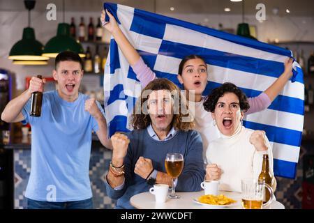 Enthusiastic Greek fans scream with joy in beer bar. Greece win Stock Photo