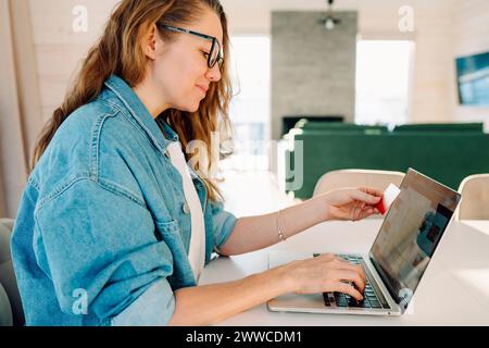 Woman with credit card making online payment through laptop at home Stock Photo