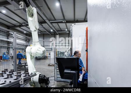 Maintenance engineer operating CNC machine with robotic arm Stock Photo