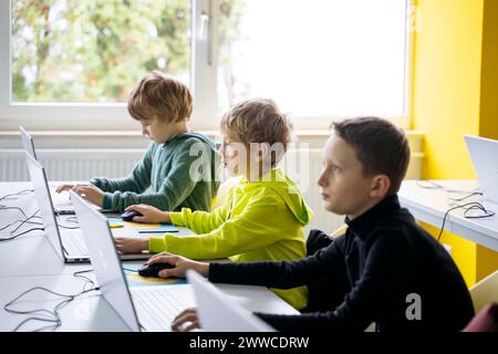 Boys using laptops learning computer coding in classroom Stock Photo
