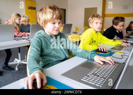 Blond boy using laptop learning computer programming at desk in classroom Stock Photo
