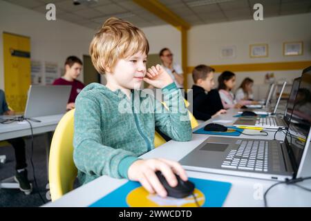 Blond boy learning computer coding through laptop in classroom Stock Photo
