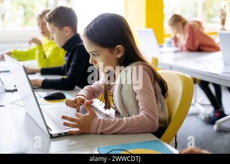 Girl using laptop for programming in classroom Stock Photo