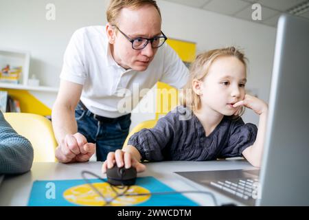 Girl using laptop by professor in classroom Stock Photo