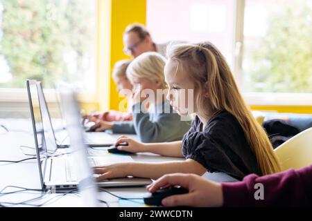 Blond girl using laptop learning computer programming in classroom Stock Photo