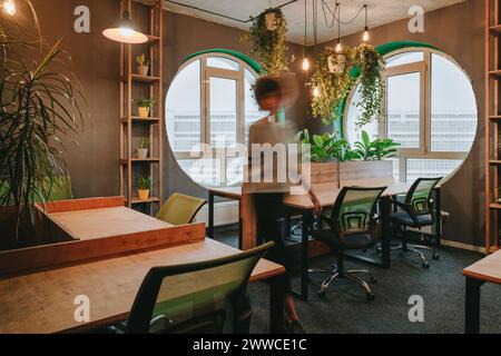 Blurred businesswoman walking amidst desks in office Stock Photo