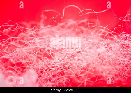 Extreme macro of polyester stable fiber on red background. Selective focus, shallow depth of field. Abstract dreamy background Stock Photo