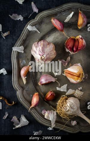 Raw garlic on grey pewter plate. Flat lay. Top view. Food concept. Dark mood food photography. Stock Photo