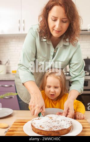 funny girl looks at fresh plum pie, emotional and cheerful. Smiling, preparing. slices cake Stock Photo