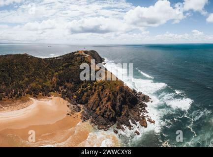 Byron Bay lighthouse high on the rocky headland - the most eastern point of Australian continent facing Pacific ocean in elevated aerial seascape Stock Photo