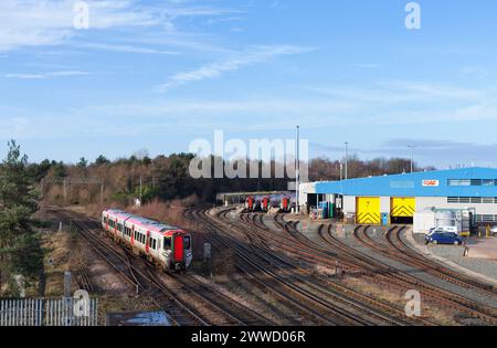 Chester, Cheshire, UK.  Transport For Wales class 197 train passing the CAF Chester train Maintenance depot with other class 197's stabled Stock Photo