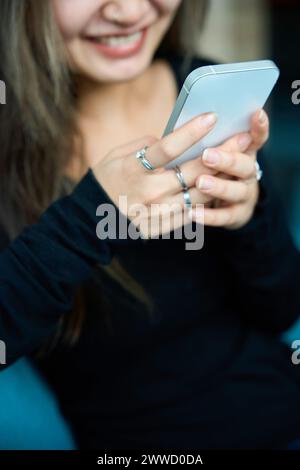 Focus on smartphone using cropped blurred young smiling asian woman Stock Photo