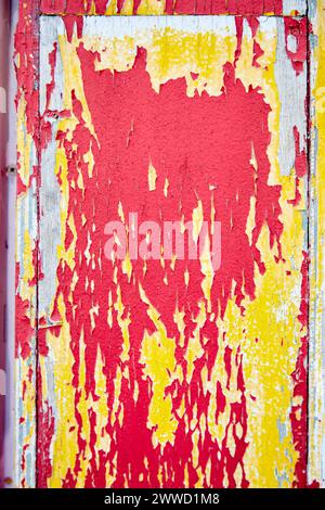 Peeling Red and Yellow Paint on a Plank of Wood Stock Photo