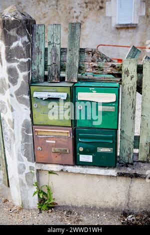 Green and Brown Mailboxes set in Broken Old Fence Stock Photo