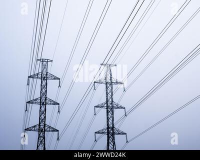 High voltage power line silhouette in foggy morning against white sky Stock Photo