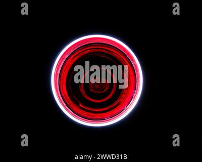 Artistic close-up of an illuminated red wine glass on a black background Stock Photo