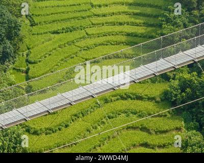 Aerial view of a Tibetan suspended bridge in Nepal is a primitive type of bridge. Wild nature, rice fields, valleys and rivers Stock Photo