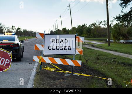 Police patrol car at yellow protective barrier at street construction site. Warning road sign about utility work Stock Photo