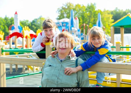 Grandmother walks with her grandchildren on playground Stock Photo