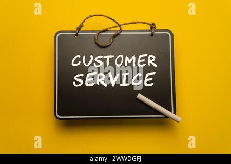 A small chalkboard for schedules on orange background with customer service words Stock Photo