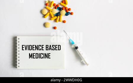Medical concept. Text EVIDENCED PRACTICE on a notepad with vaccine and pills on a white background. Stock Photo