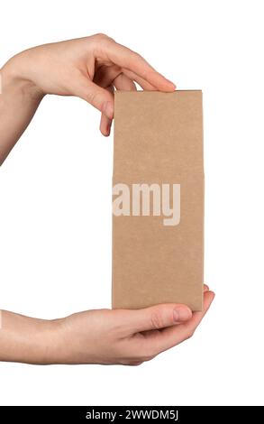 A hand holding a brown kraft cardboard box. Craft paper package of rectangular shape, mockup, isolated on white background Stock Photo